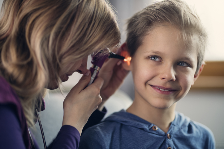 A doctor is using a torch to look into a child's ear
