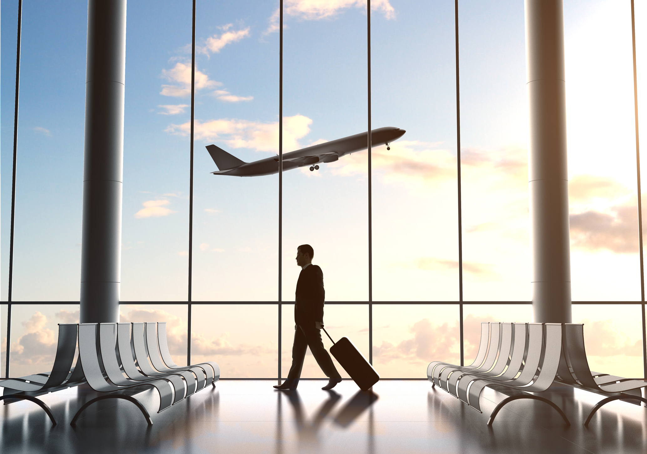 A man at the airport with a plane flying in the background