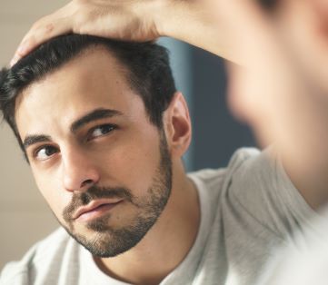 man checking his hair in the mirror for signs of male pattern baldness