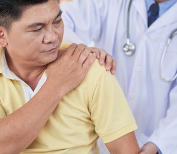 Consultant examining man's shoulder for rotator cuff injury