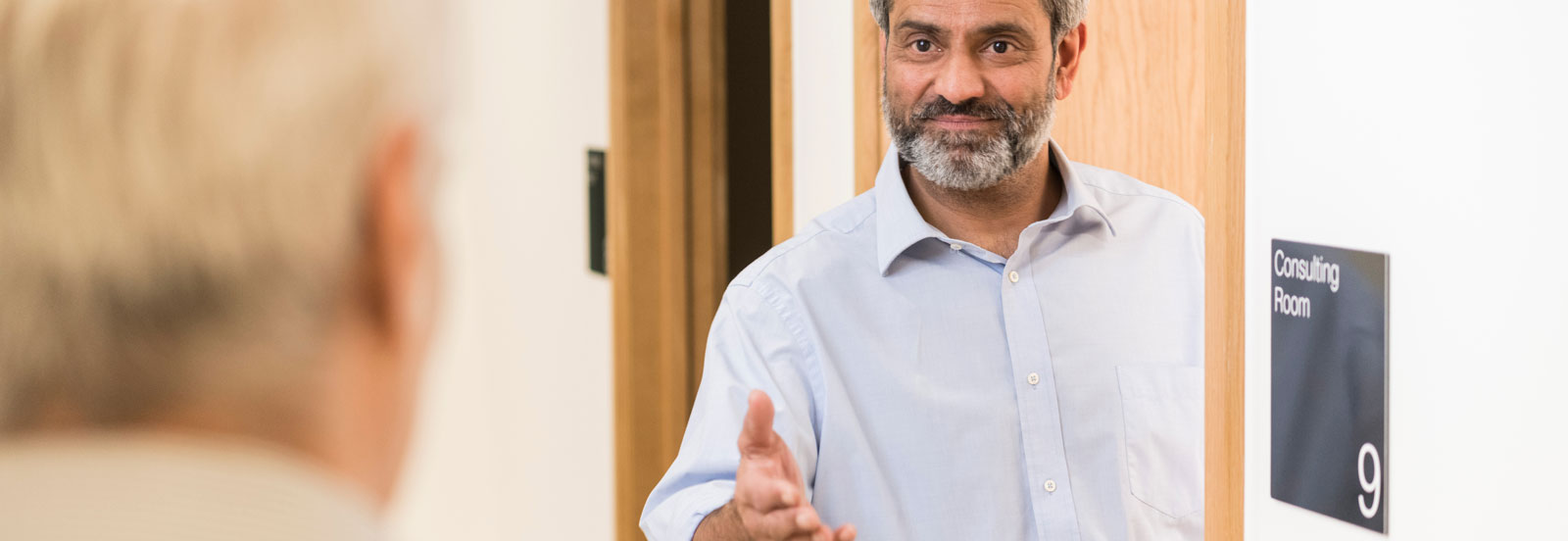 Friendly consultant welcomes a patient into his room