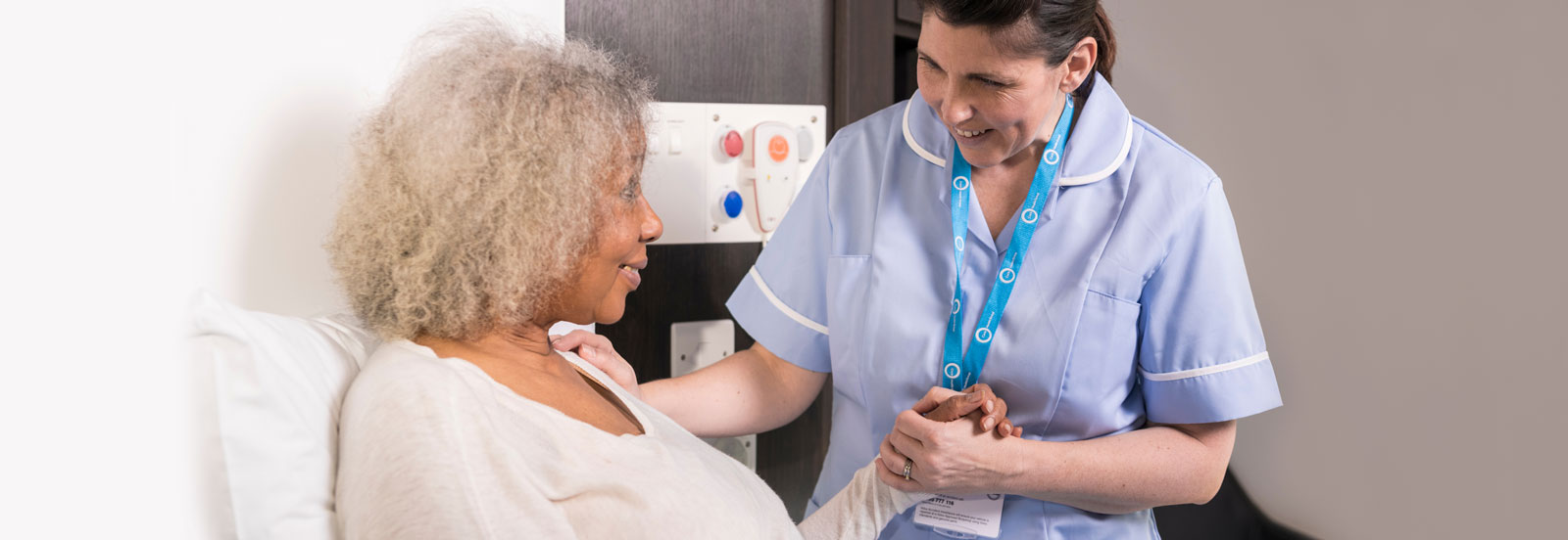 Older woman being comforted by a smiling cancer nurse