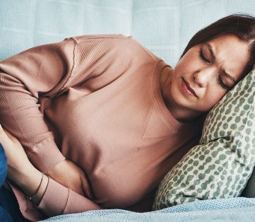 woman on sofa in severe pain from undiagnosed endometriosis