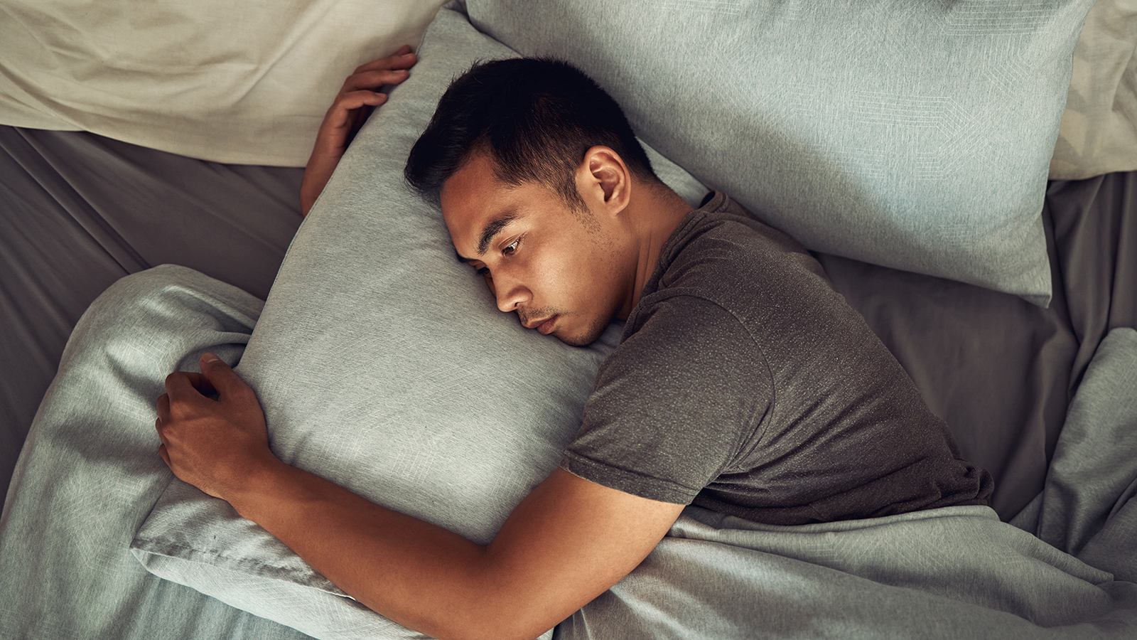 man with painsomnia lying awake in bed