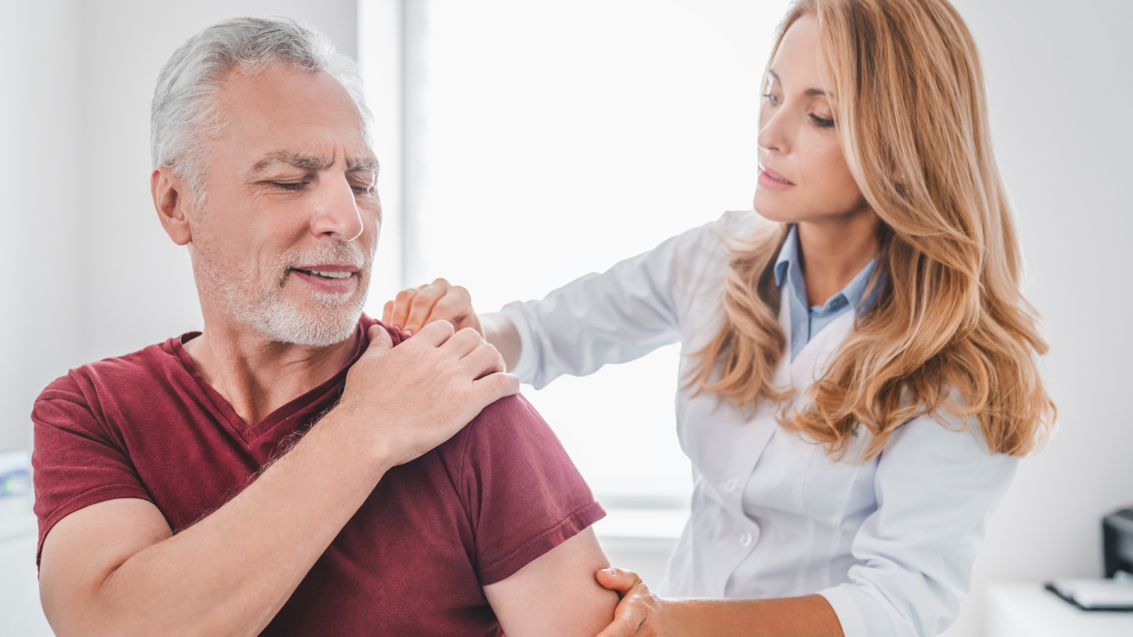 Female consultant examining male patient's shoulder - What is a shoulder replacement?