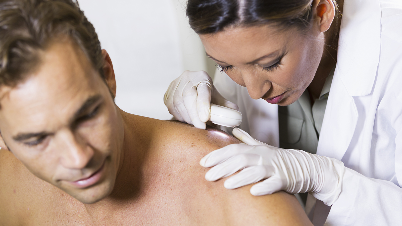 consultant checking patient's skin for signs of skin cancer
