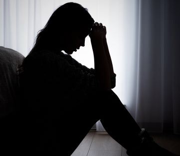 woman with depression silhouetted in a dimly lit room