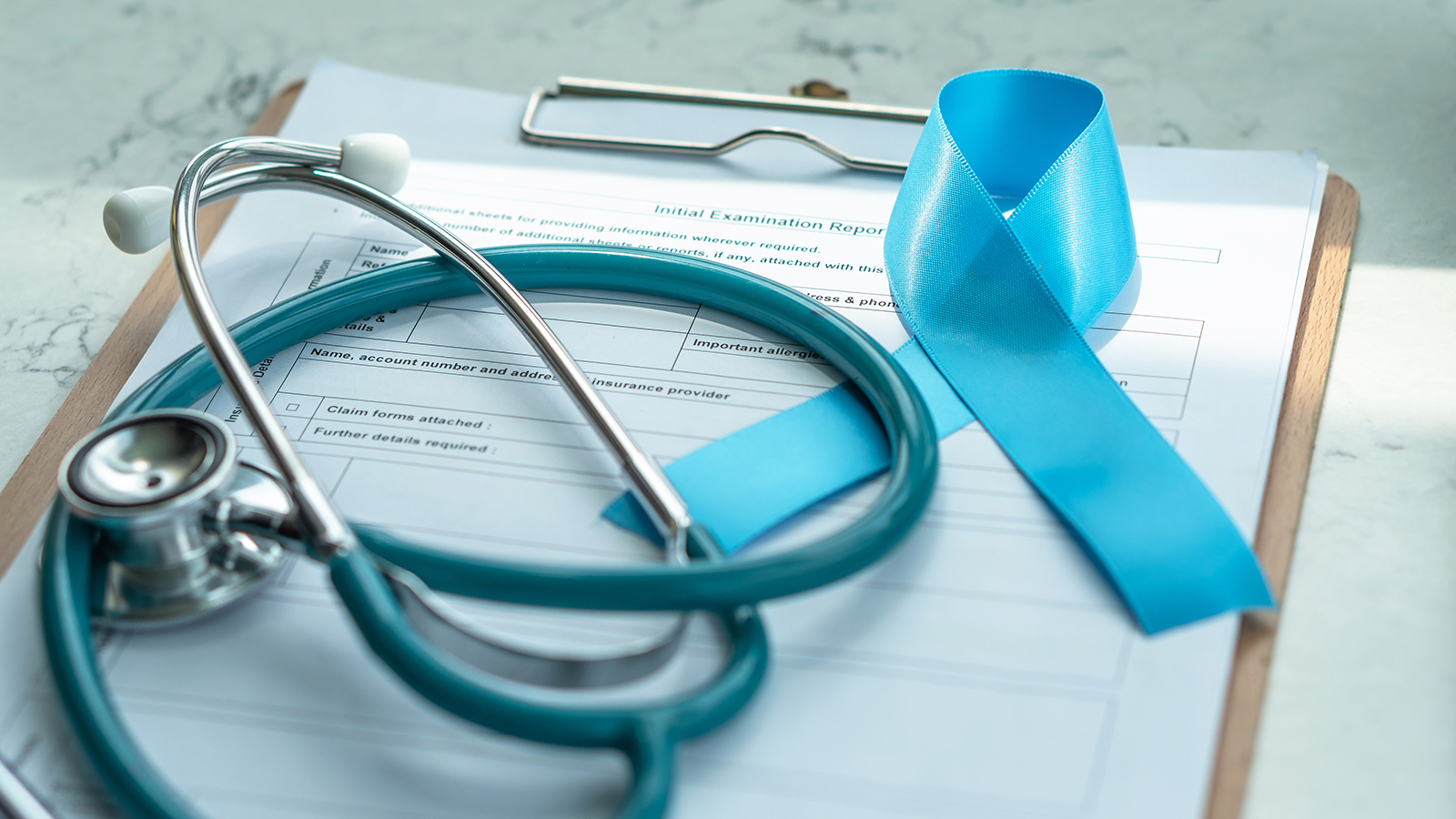 doctor's charts with stethoscope and a blue ribbon symbolising prostate cancer