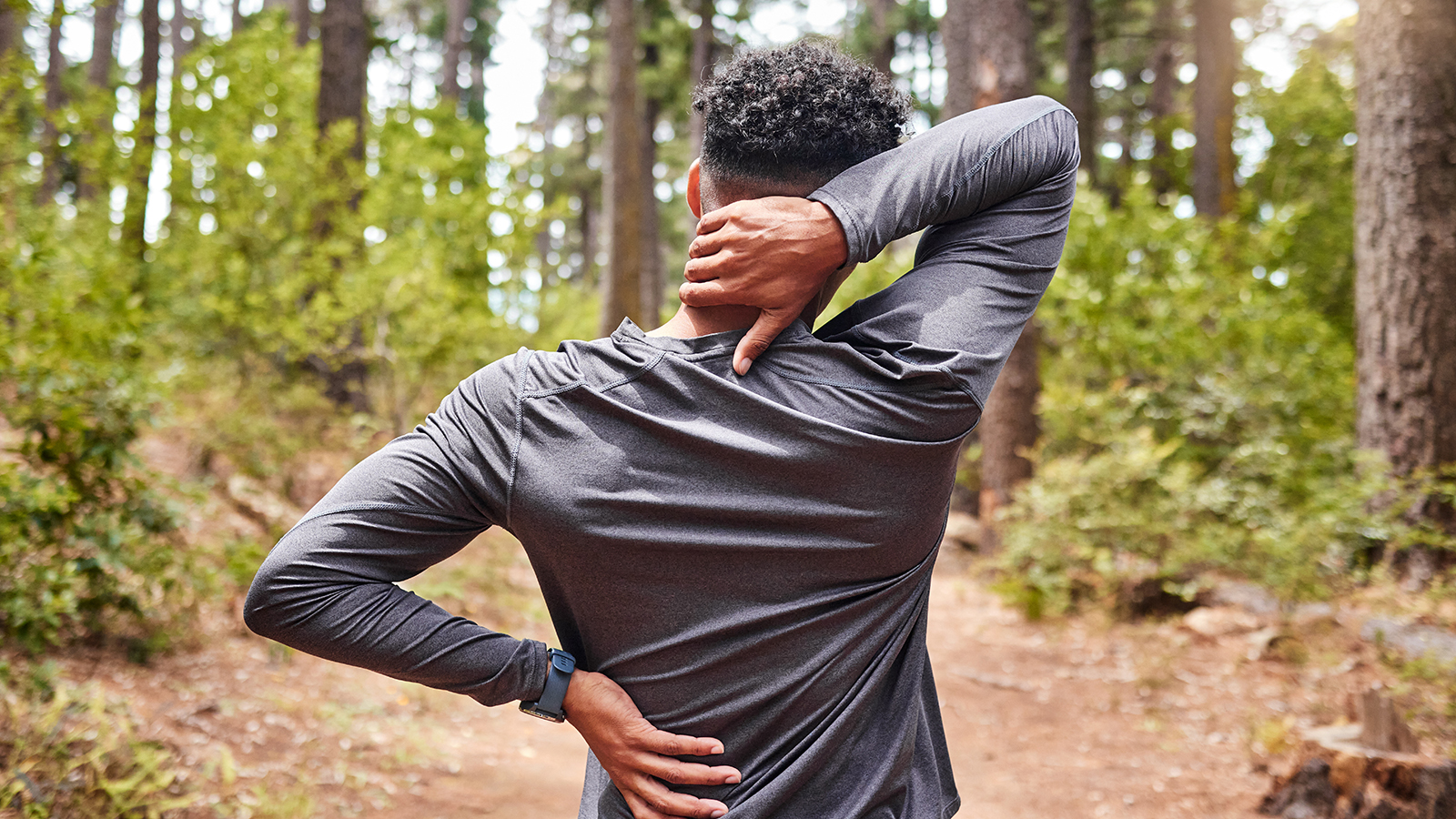 young man pauses running in the woods due to joint pain