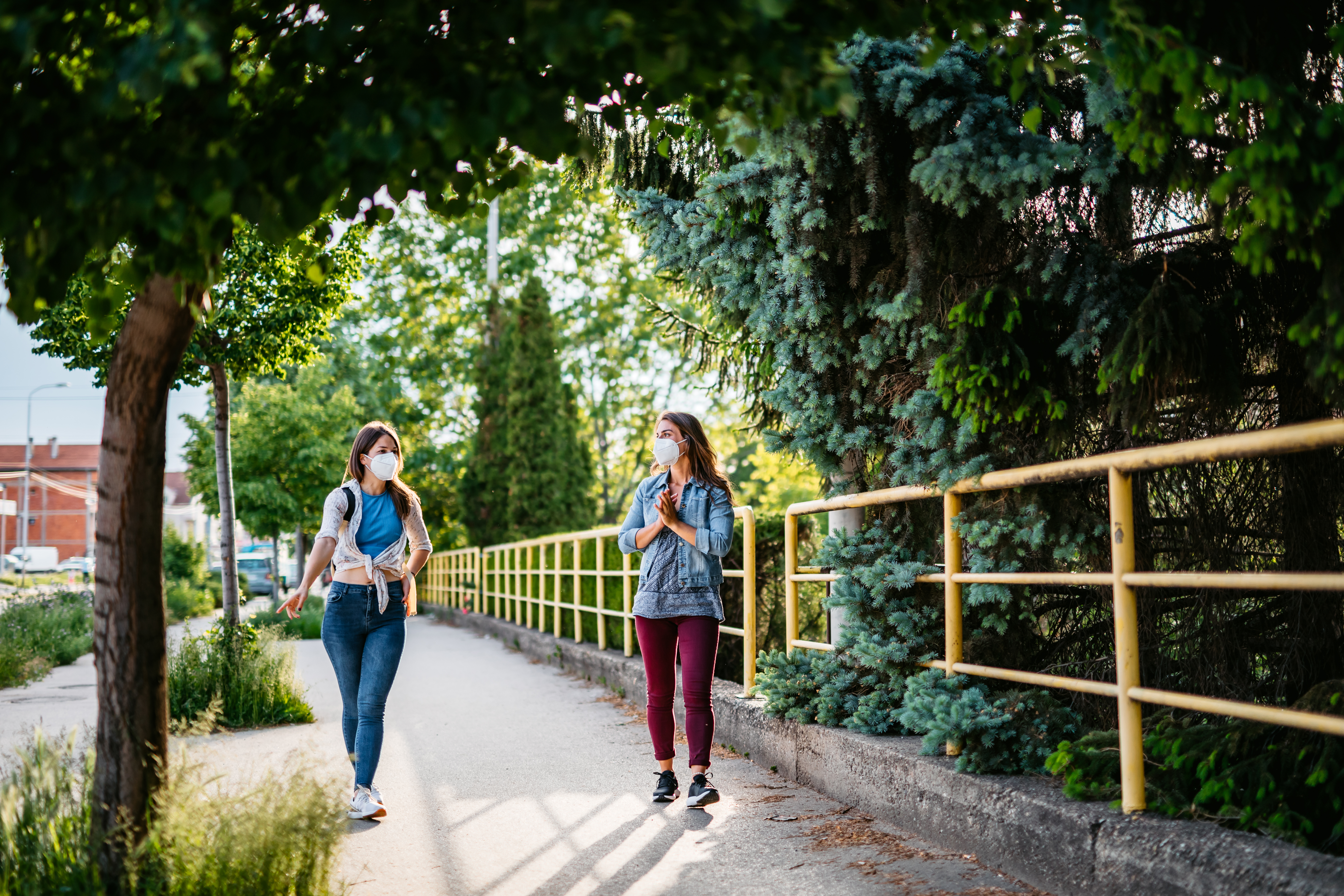 Two women with face masks walk down the street