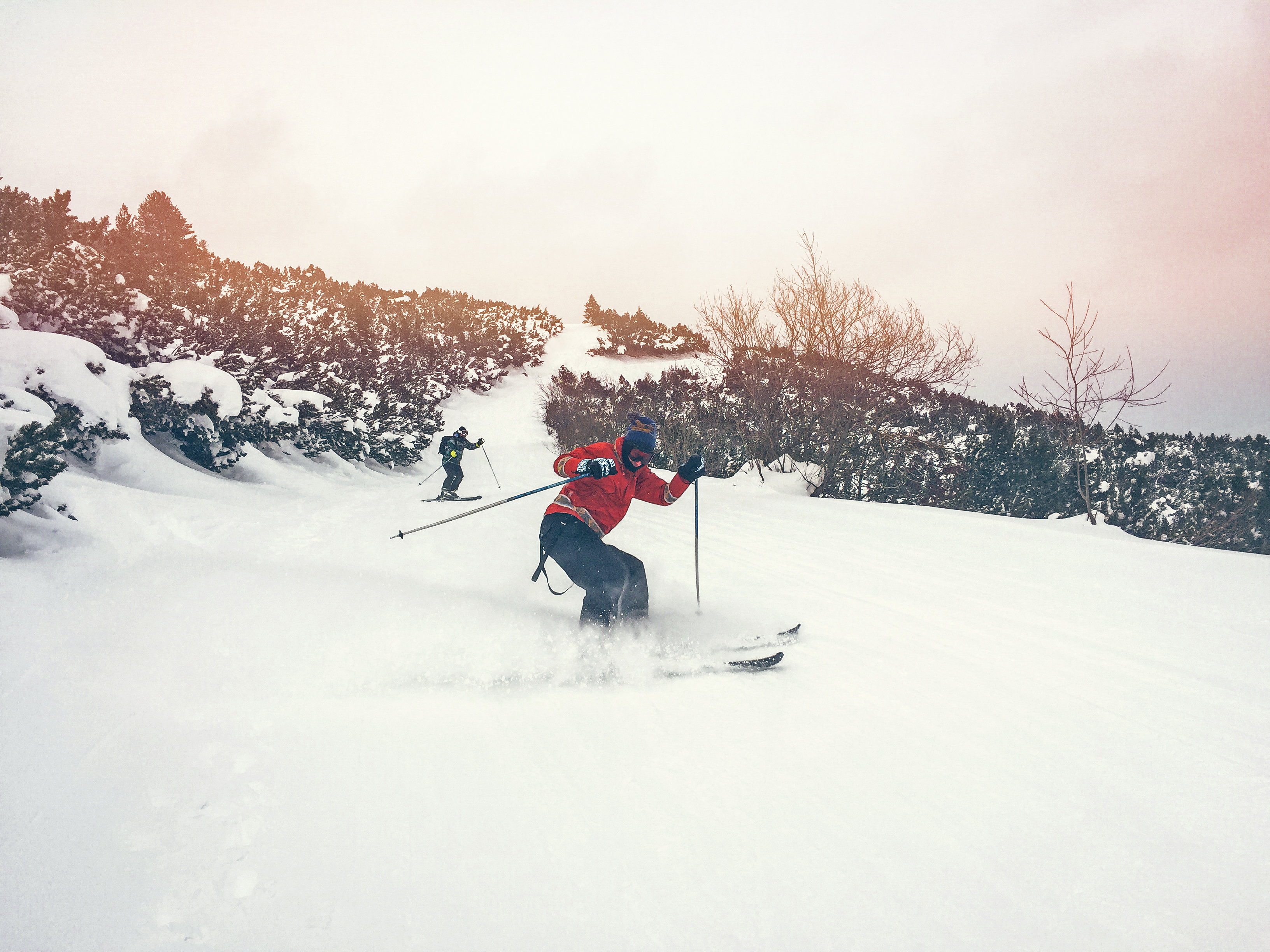 Two individuals skiing down a snowy mountain