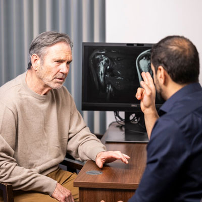 Patient speaking with a healthcare professional while reviewing medical scans displayed on a screen during a consultation