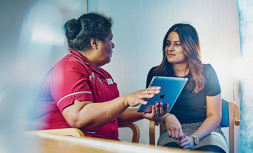 female patient showing notes on digital tablet to her female patient