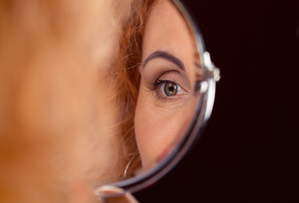 Lady looking in the mirror at her eyelids after surgery