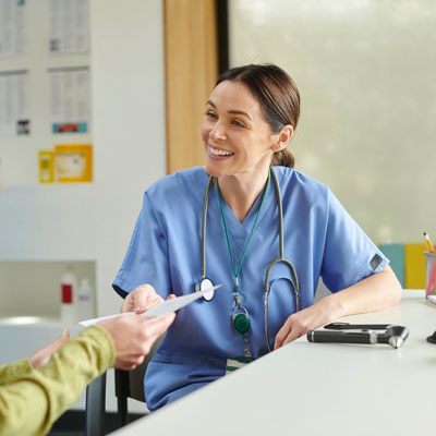 Healthcare professional seated at a desk speaking with a patient