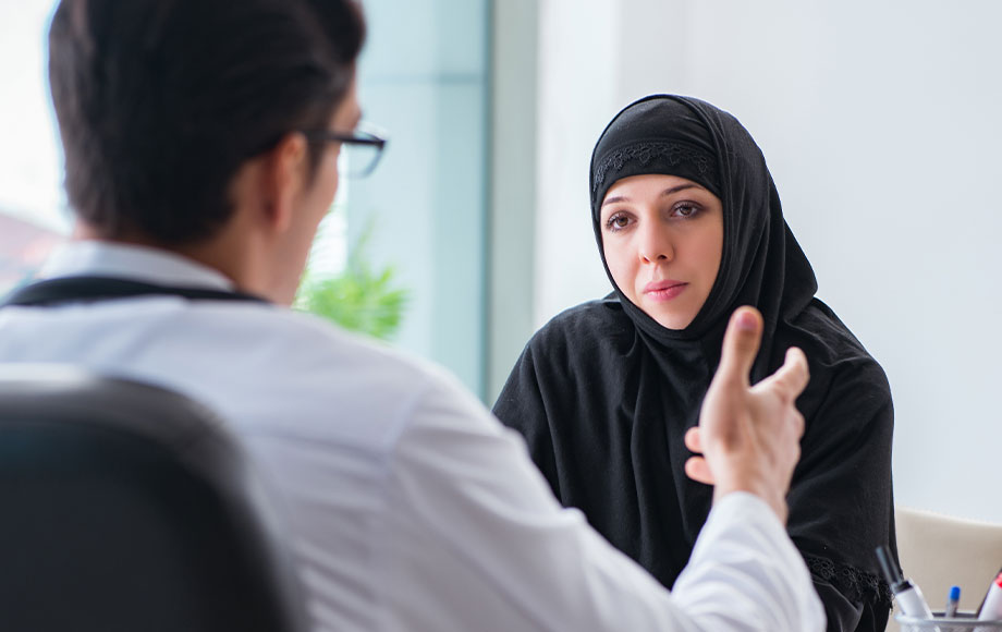 Muslim woman wearing hijab speaking to surgeon in consultation