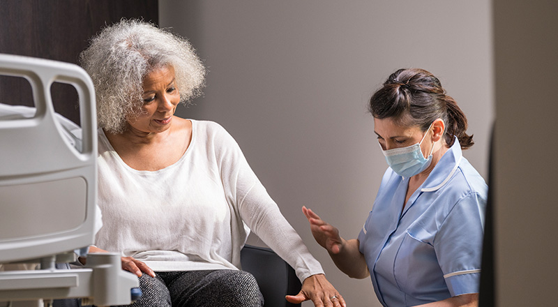 A caring nurse assisting an elderly woman in a hospital bed providing comfort and support