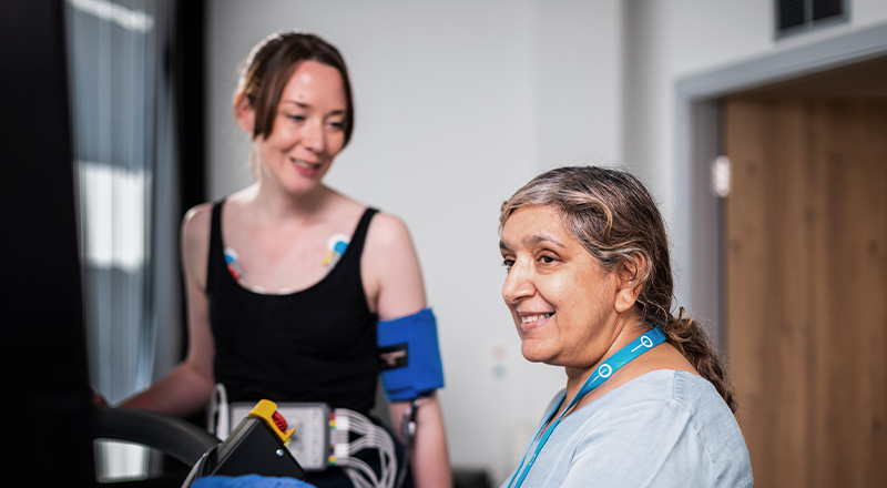 A woman conversing with another woman in a hospital room