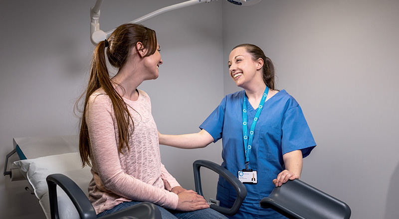 A woman sitting in a chair with a doctor discussing her health