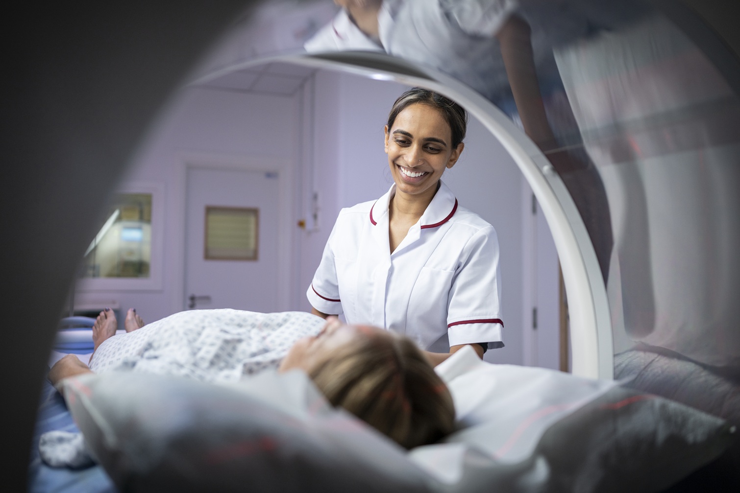 Private hospital staff member standing next to patient in scanner