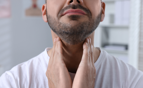 Man feeling neck due to a possible underactive thyroid