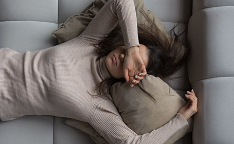 woman with fatigue caused by endomeytriosis lies down looking sad