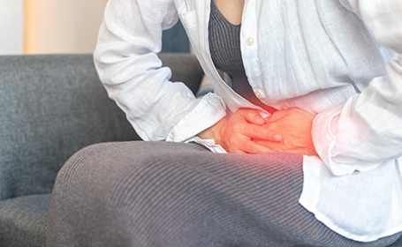 woman clutching stomach with the pain of gallstones symptoms