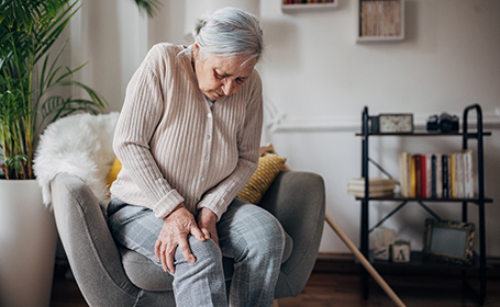 elderly woman clutching knee suffering from knee arthritis