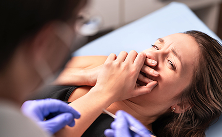 woman covering her mouth in fear of the dentist