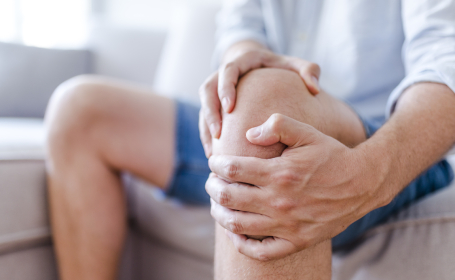 Patient holding their knee in pain due to potentially needing partial knee replacement surgery