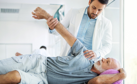 Male consultant examining male patient's shoulder - What is a shoulder replacement?