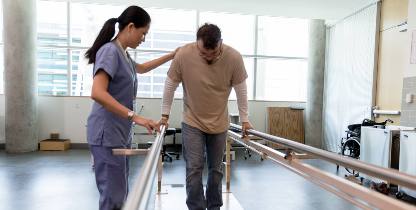 physiotherapist helping man walk again after surgery
