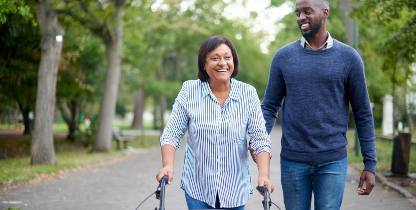 woman walking in the park using walker while recovering from hip surgery