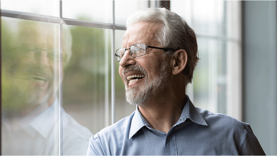 old man smiling next to a window