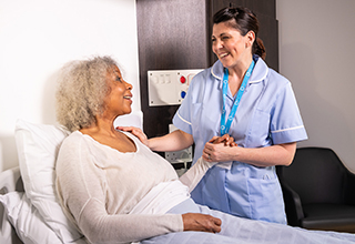 Senior patient in a bed being comforted by a nurse