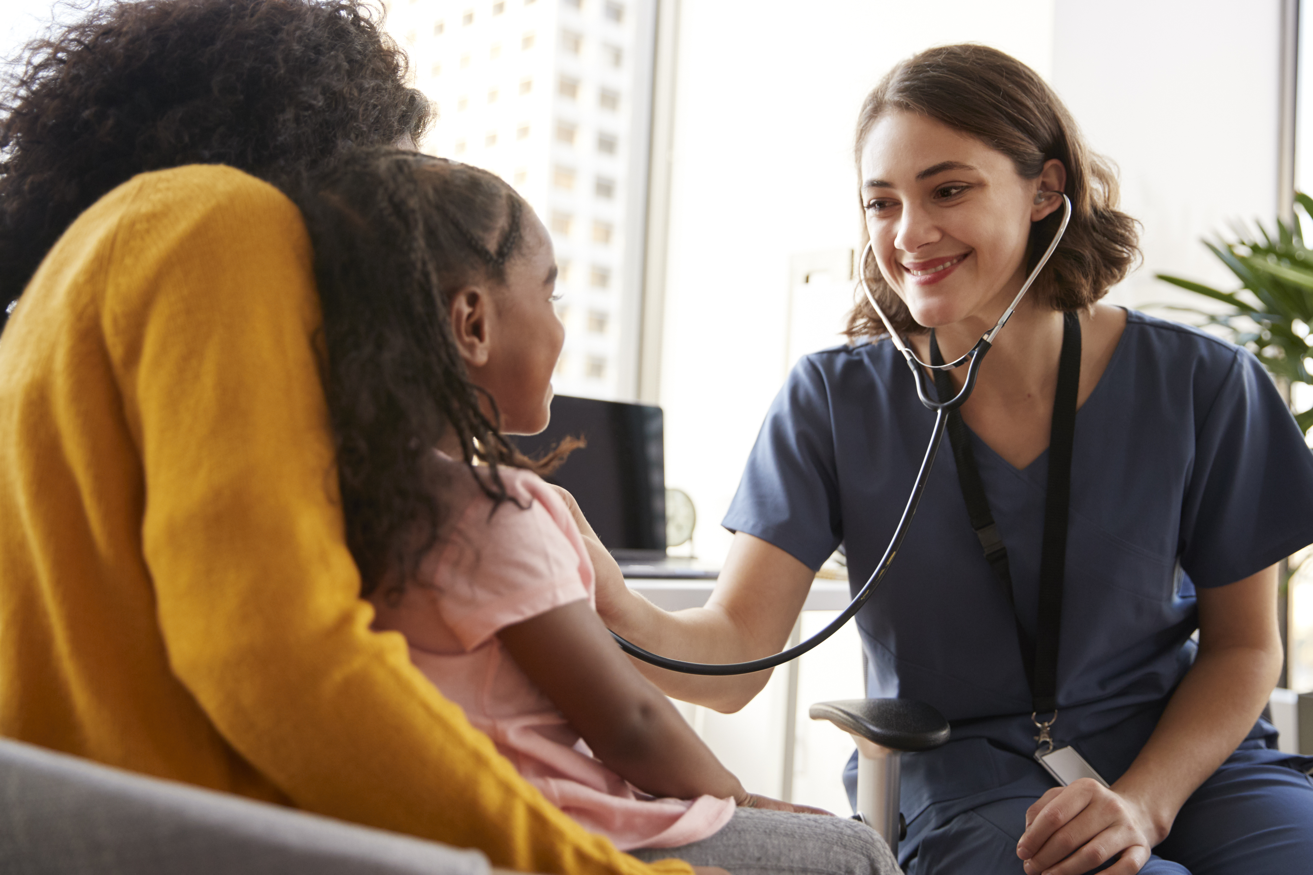 A female doctor listening to a young girl's chest with a stethoscope