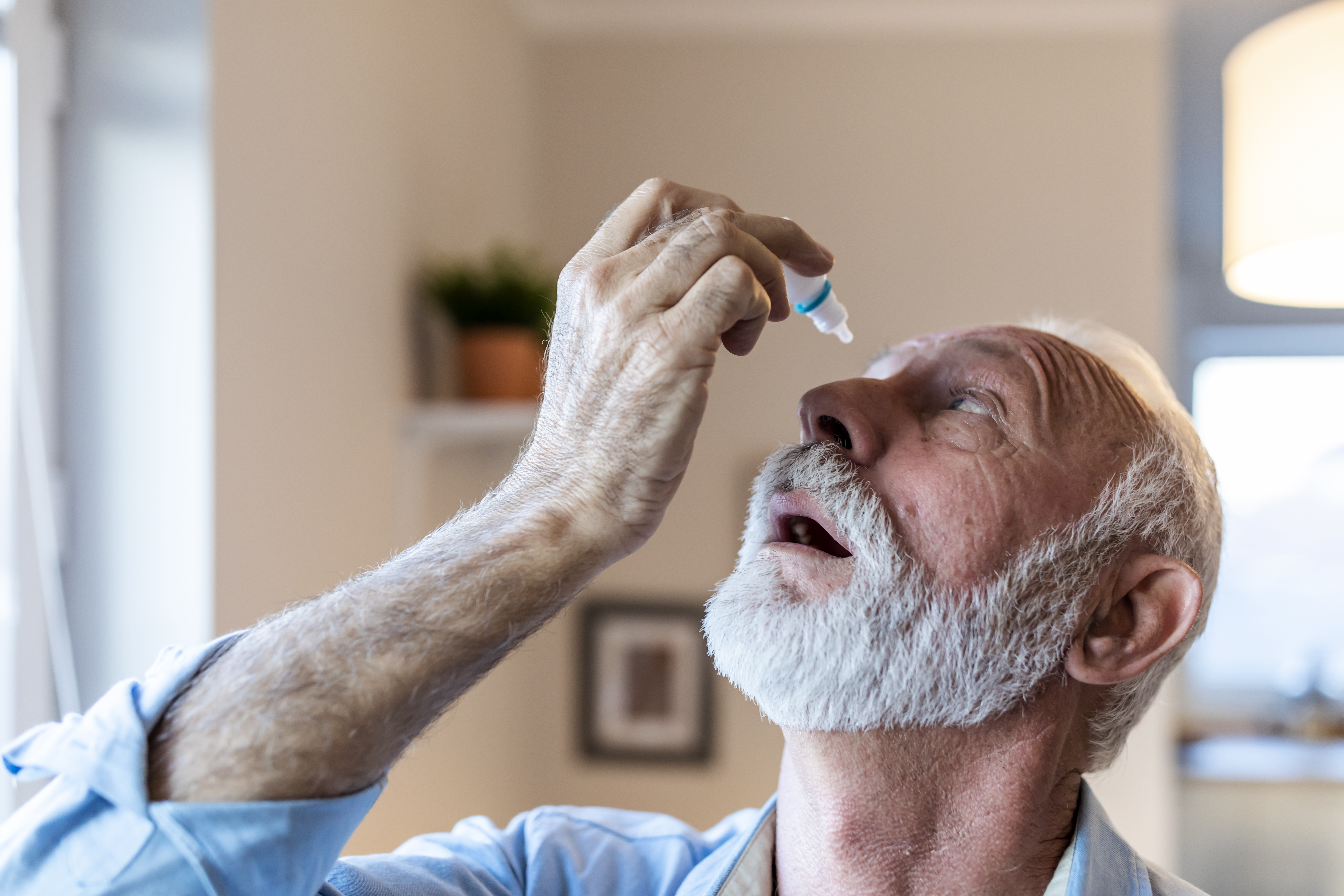 A man puts eye drops into his eyes