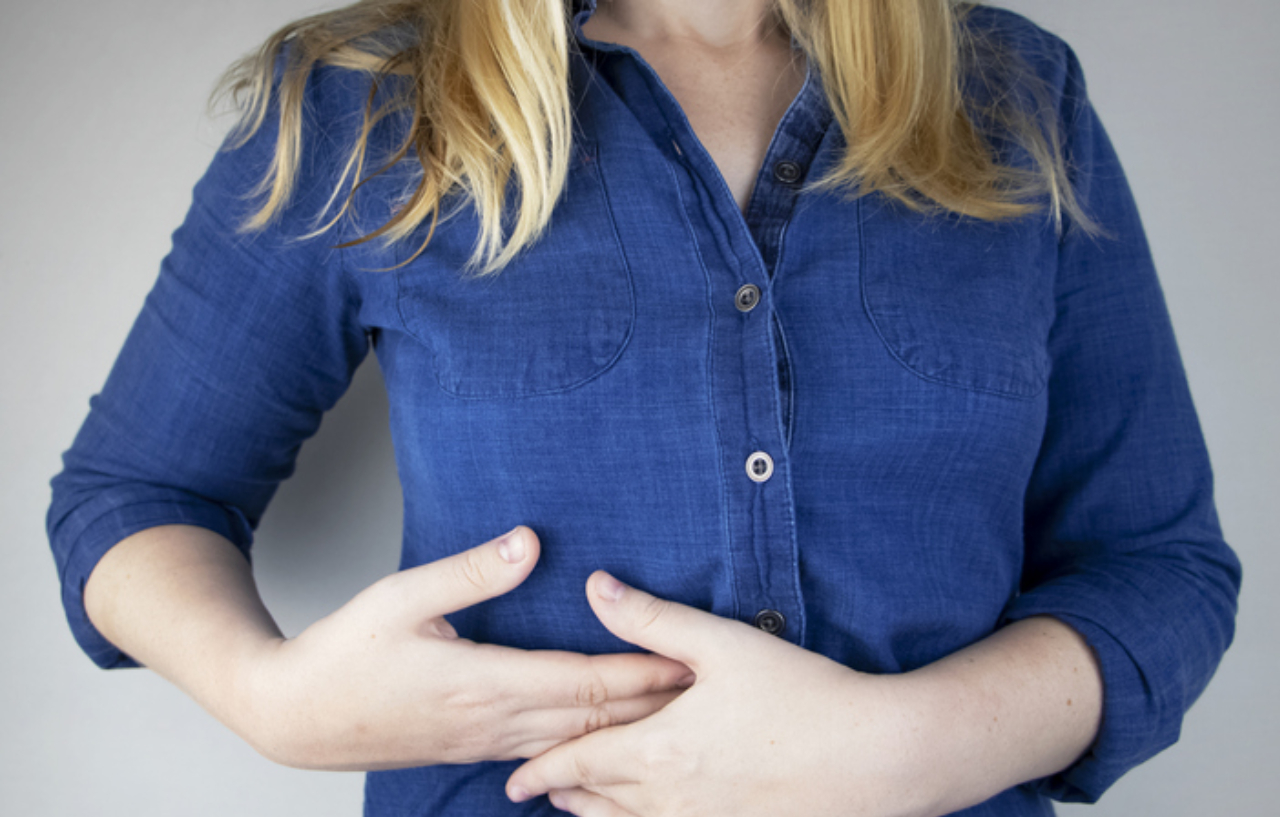 Woman needing liver cancer treatment holds onto the upper right side of her abdomen