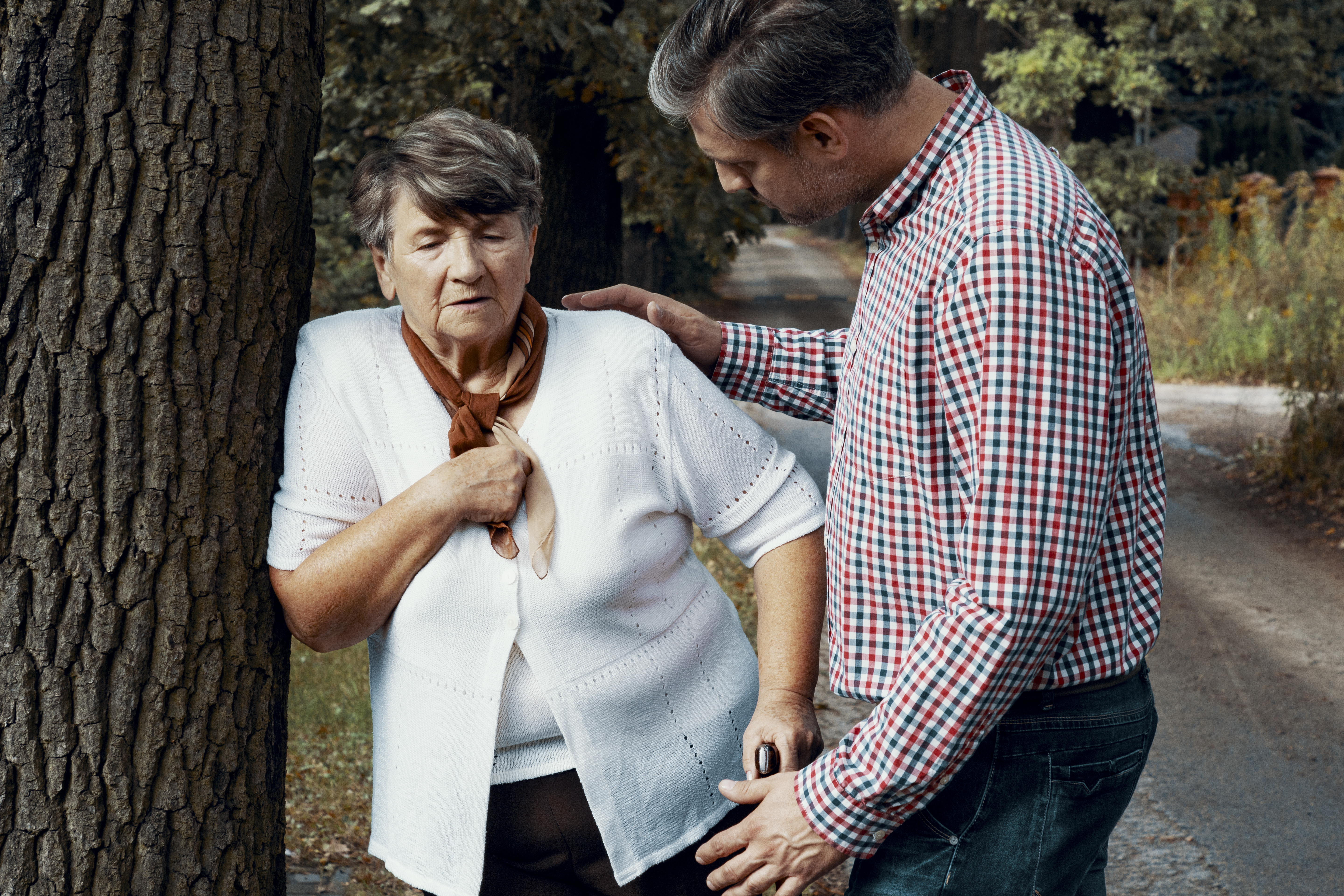 A person taking care of senior woman struggling to breath on the street