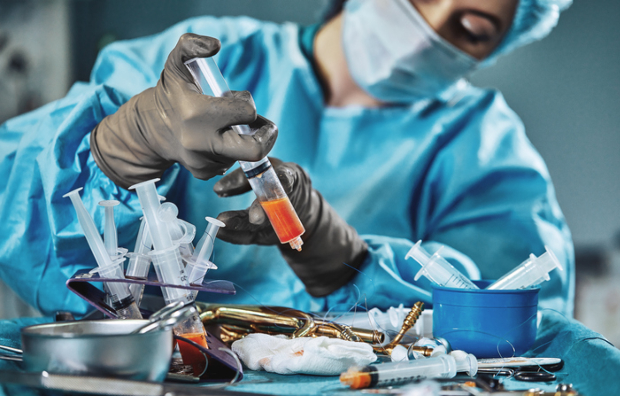 Surgeon performing fat transfer surgery and holding a syringe