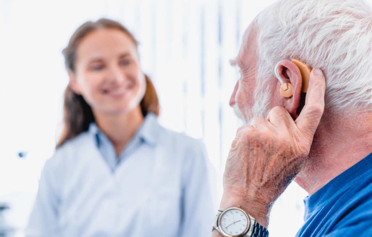 Audiologist performs a hearing aid fitting for a patient