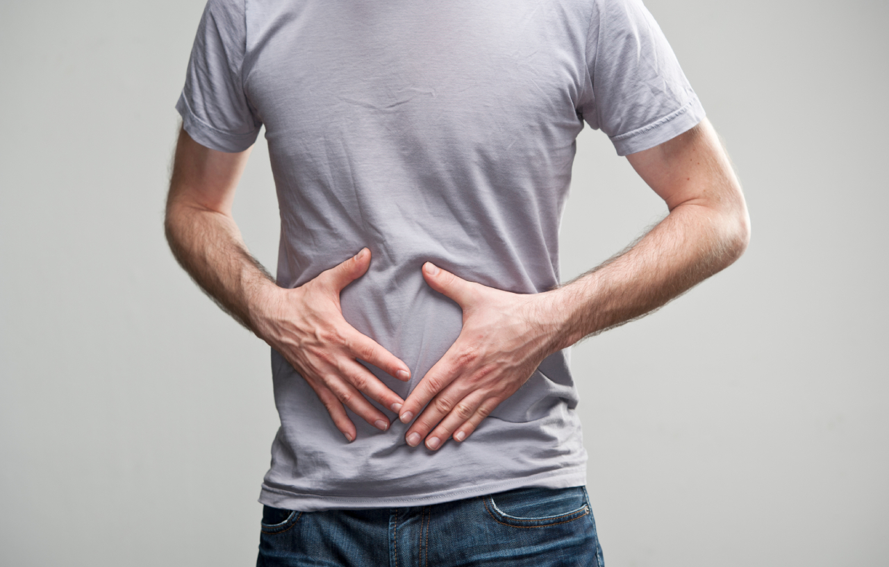 Man needing a flexible sigmoidoscopy holds his stomach in discomfort