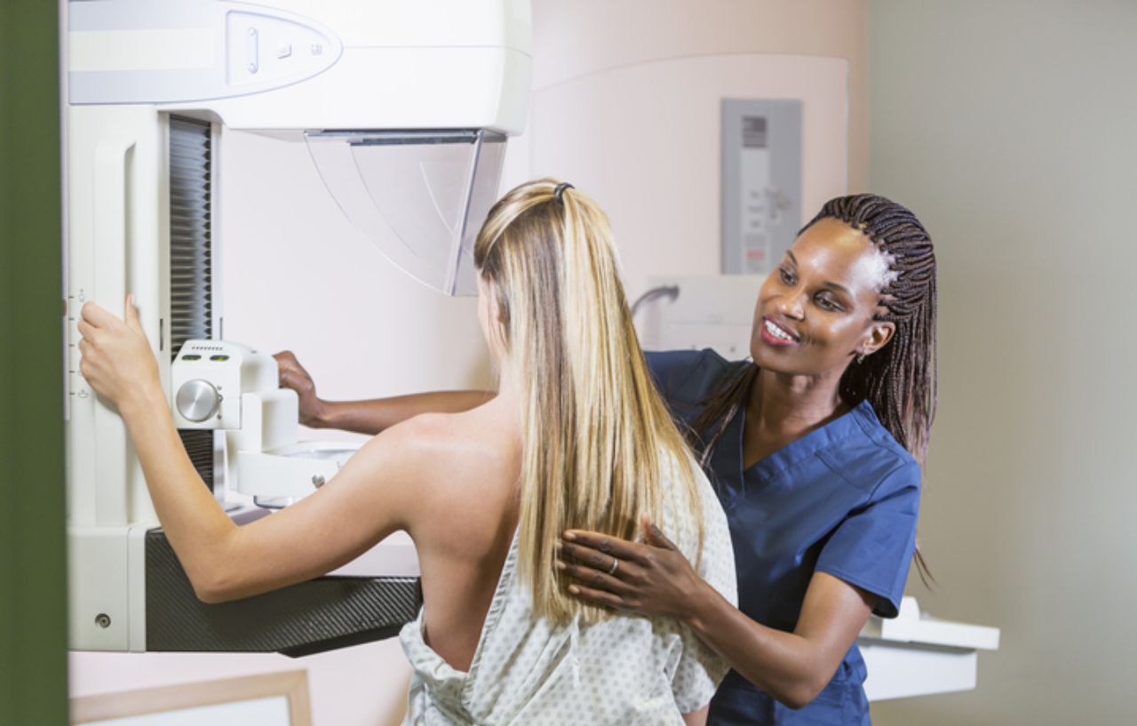 Nurse helps a woman with a mammogram machine for breast cancer screening