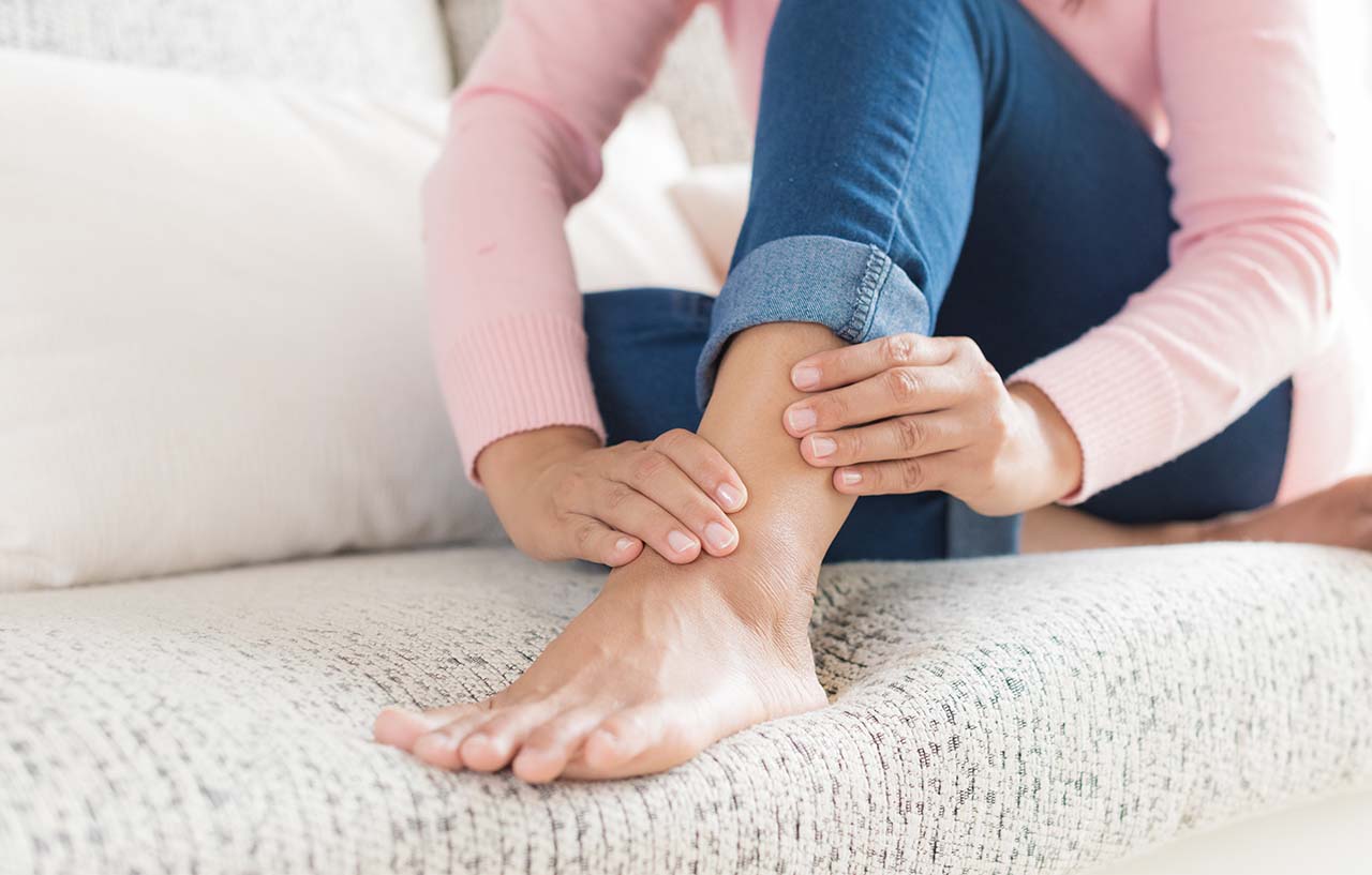 Woman on sofa inspects her ankle after her deformity limb reconstruction surgery