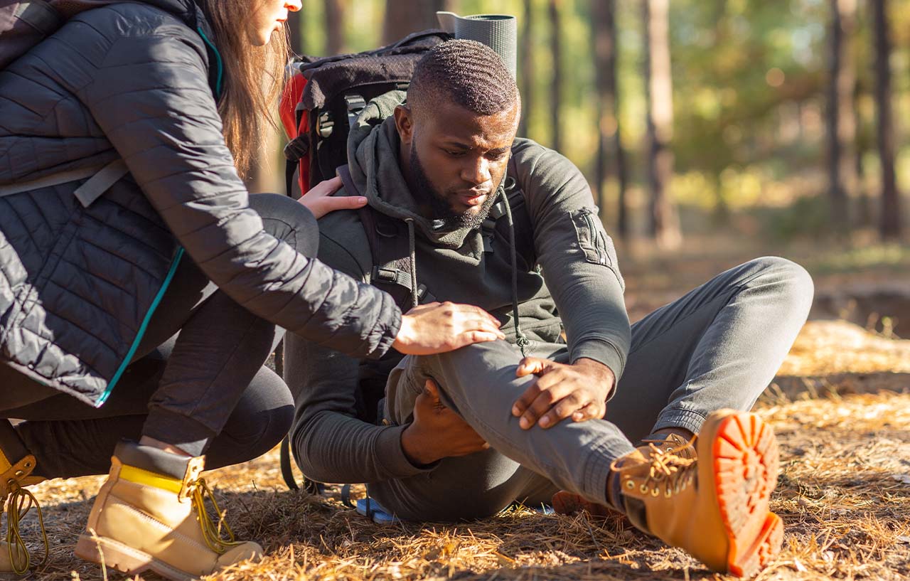 Hiker with a dislocated knee is helped by a friend