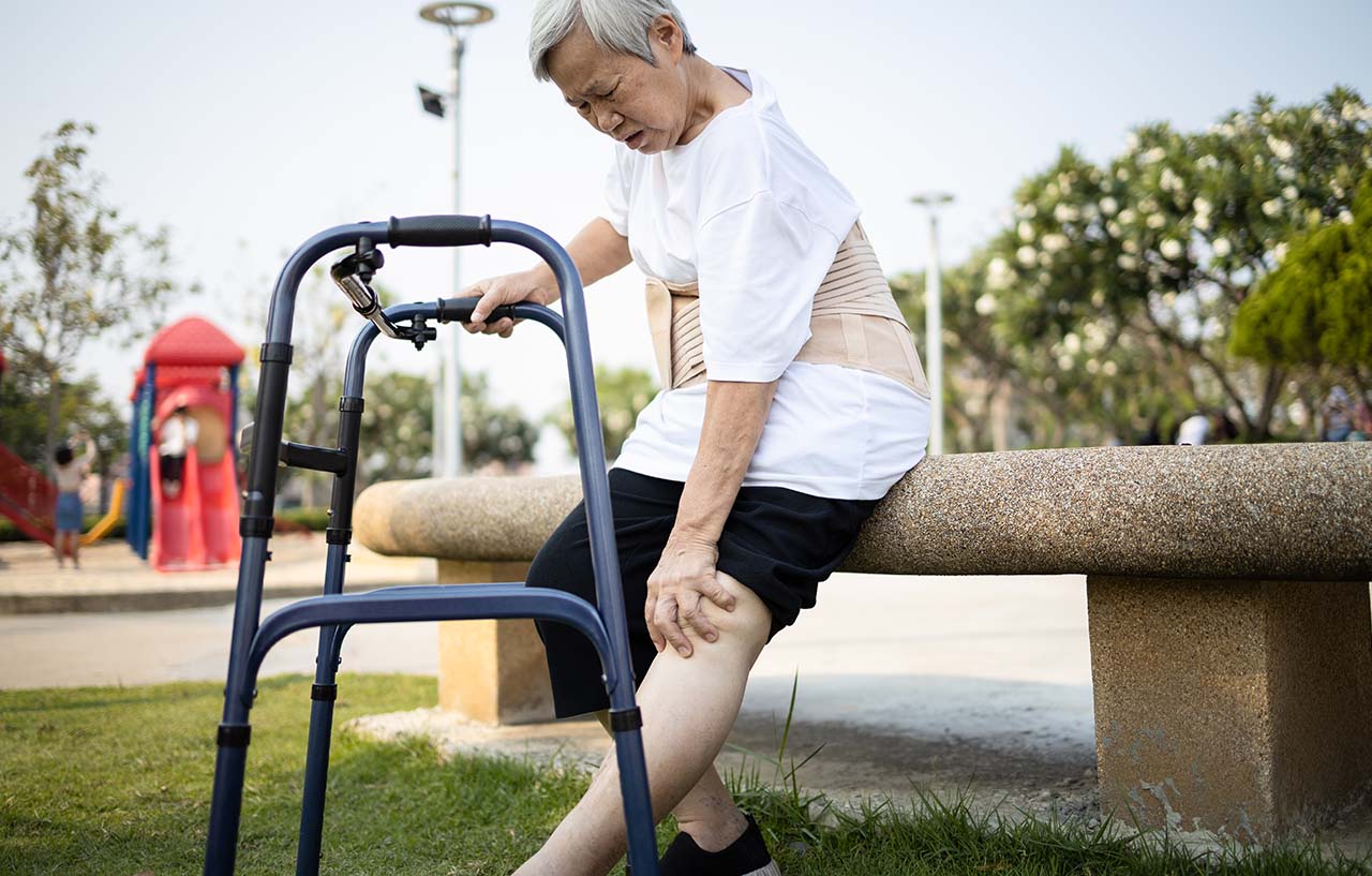 elder asian woman holding knee in pain