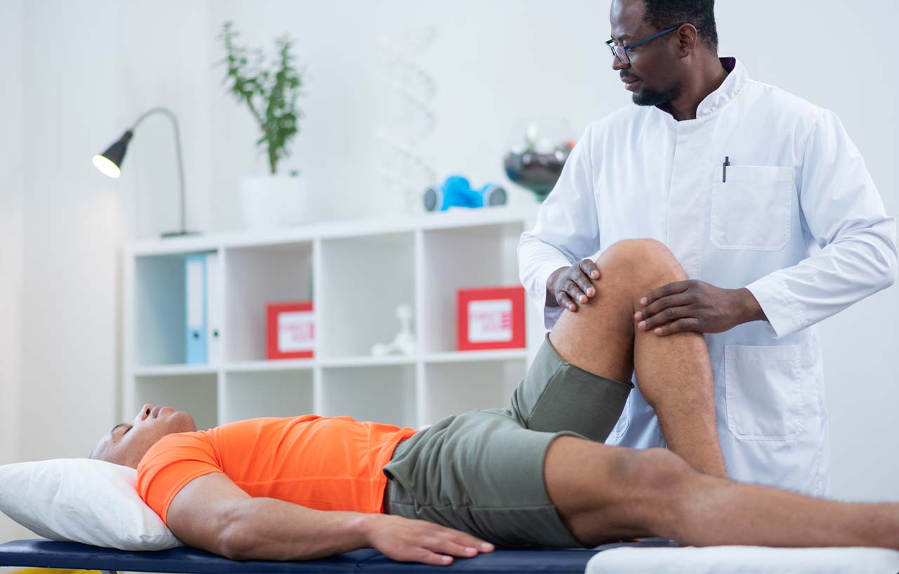 Surgeon examining a patient's knee after their kneecap stabilisation surgery procedure