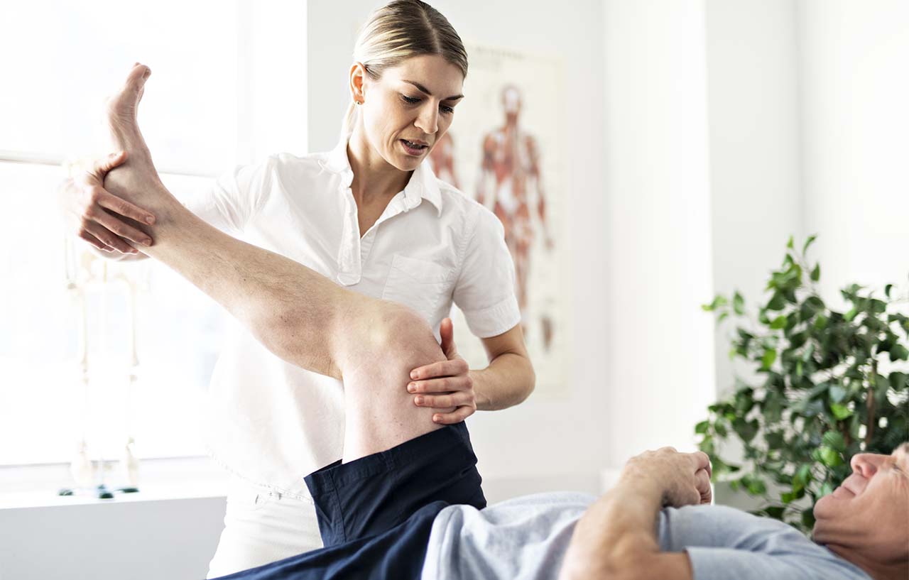 clinician performing physiotherapy on knee patient
