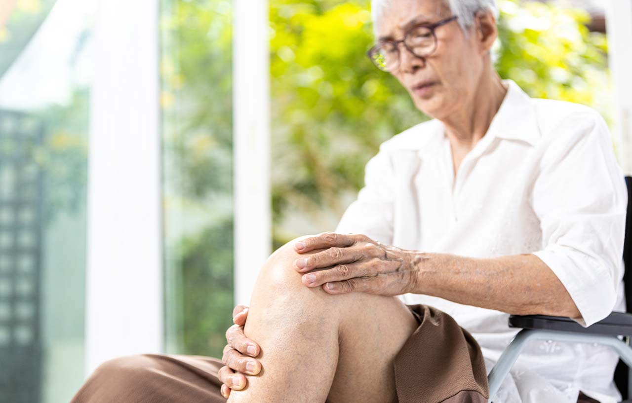 A patient with iliotibial band syndrome holds their knee and lower thigh in pain