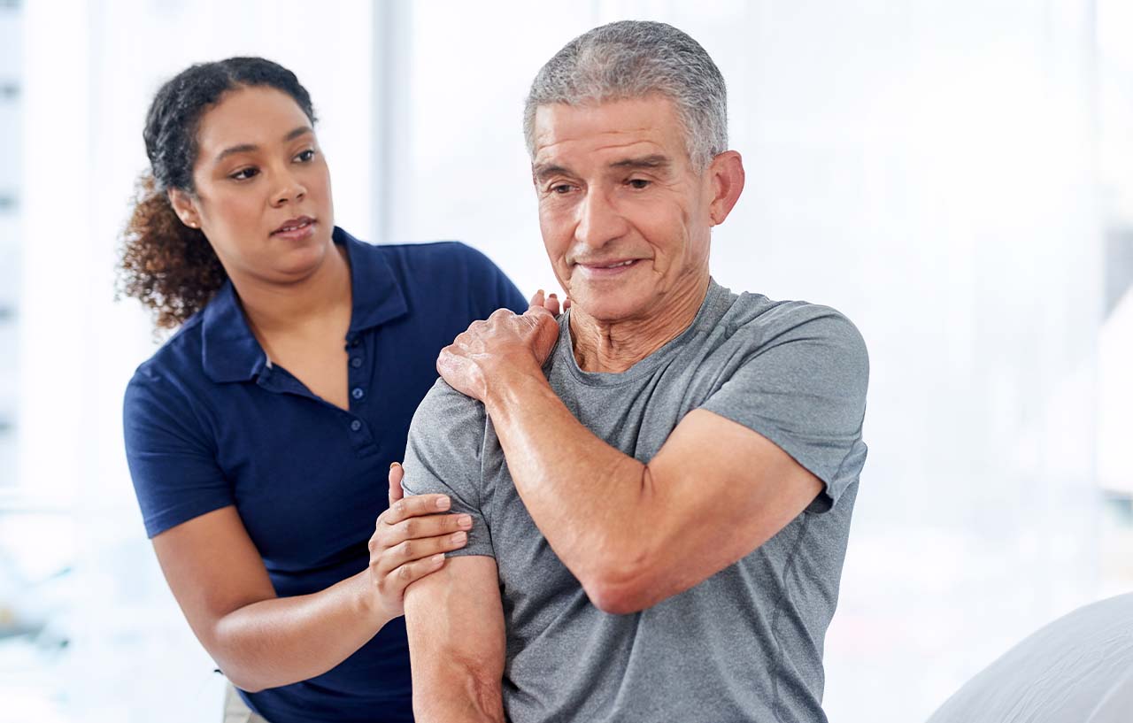 Physiotherapist examining a patient's painful shoulder in an occupational health consultation